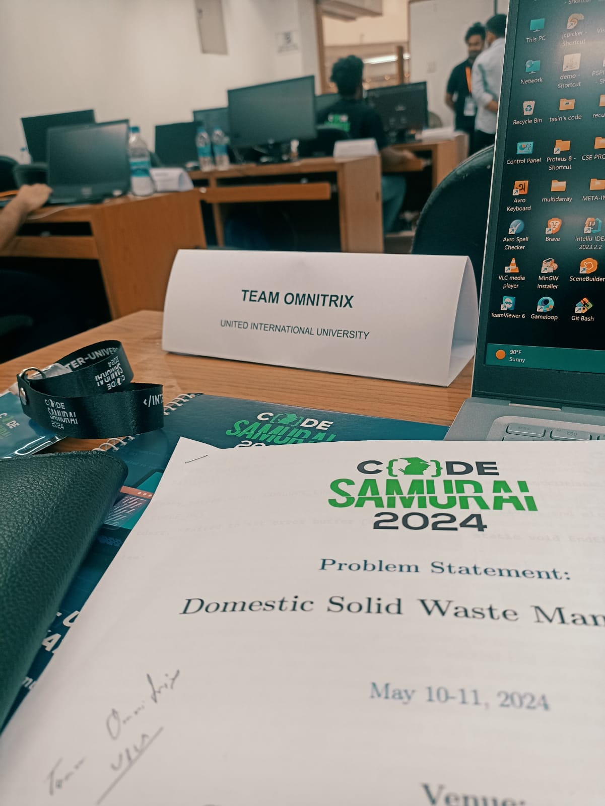 A Code Samurai 2024 desk with the Team Omnitrix name card and the printed problem statement for domestic solid waste management.